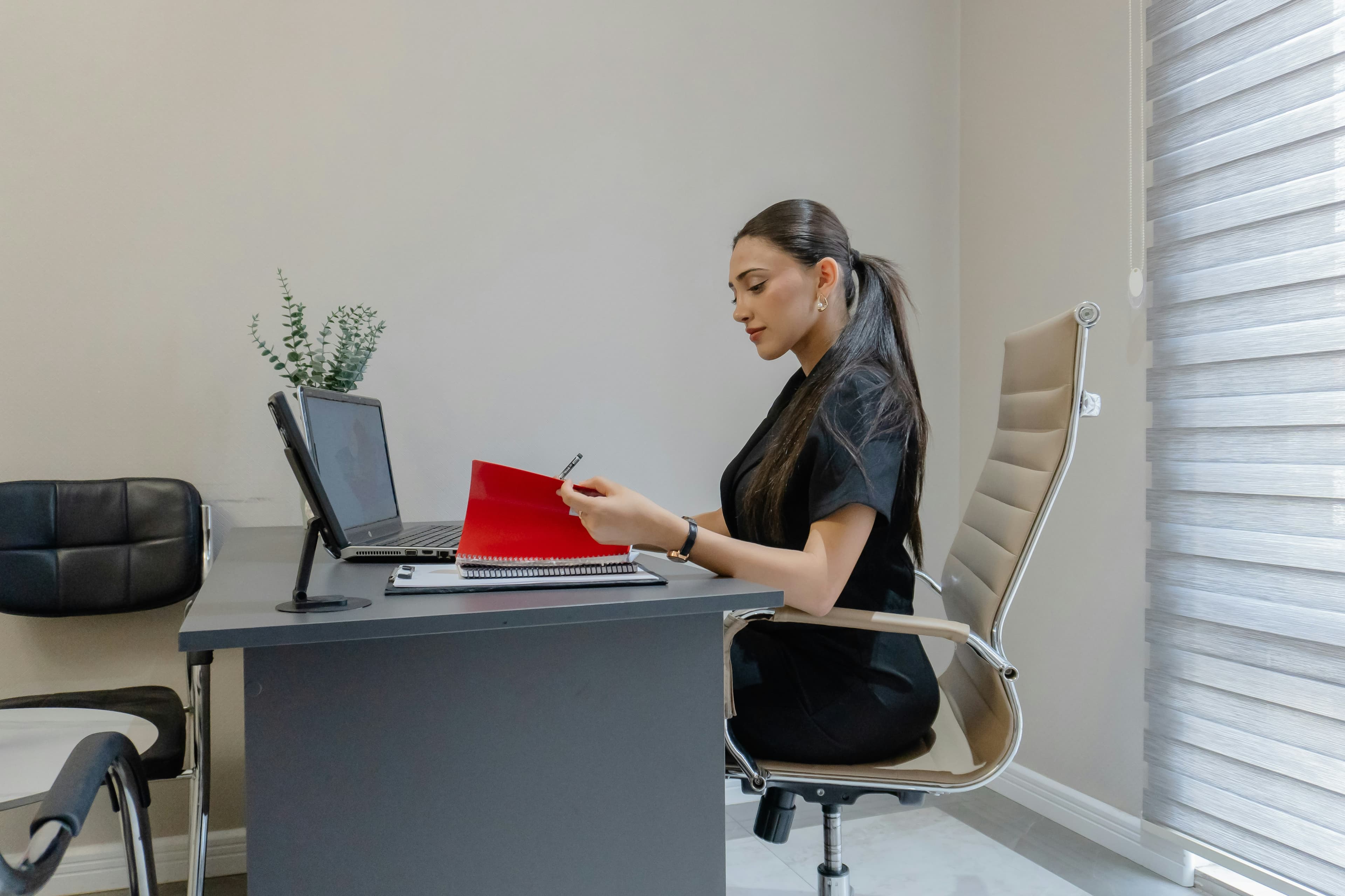Woman working at a desk with a laptop and laptop