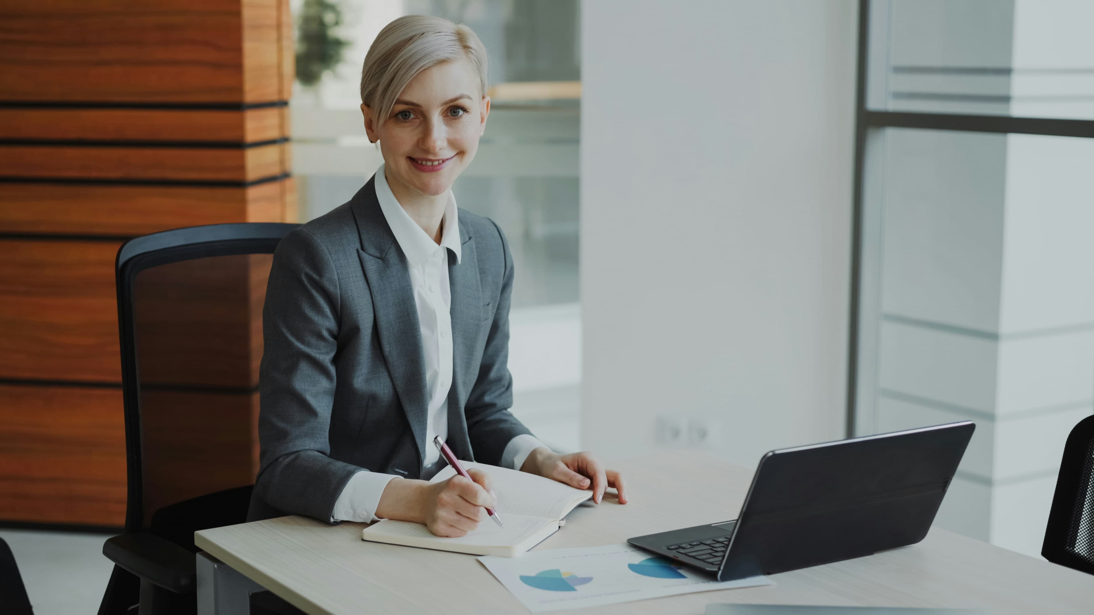 A professional woman in a suit works at a desk