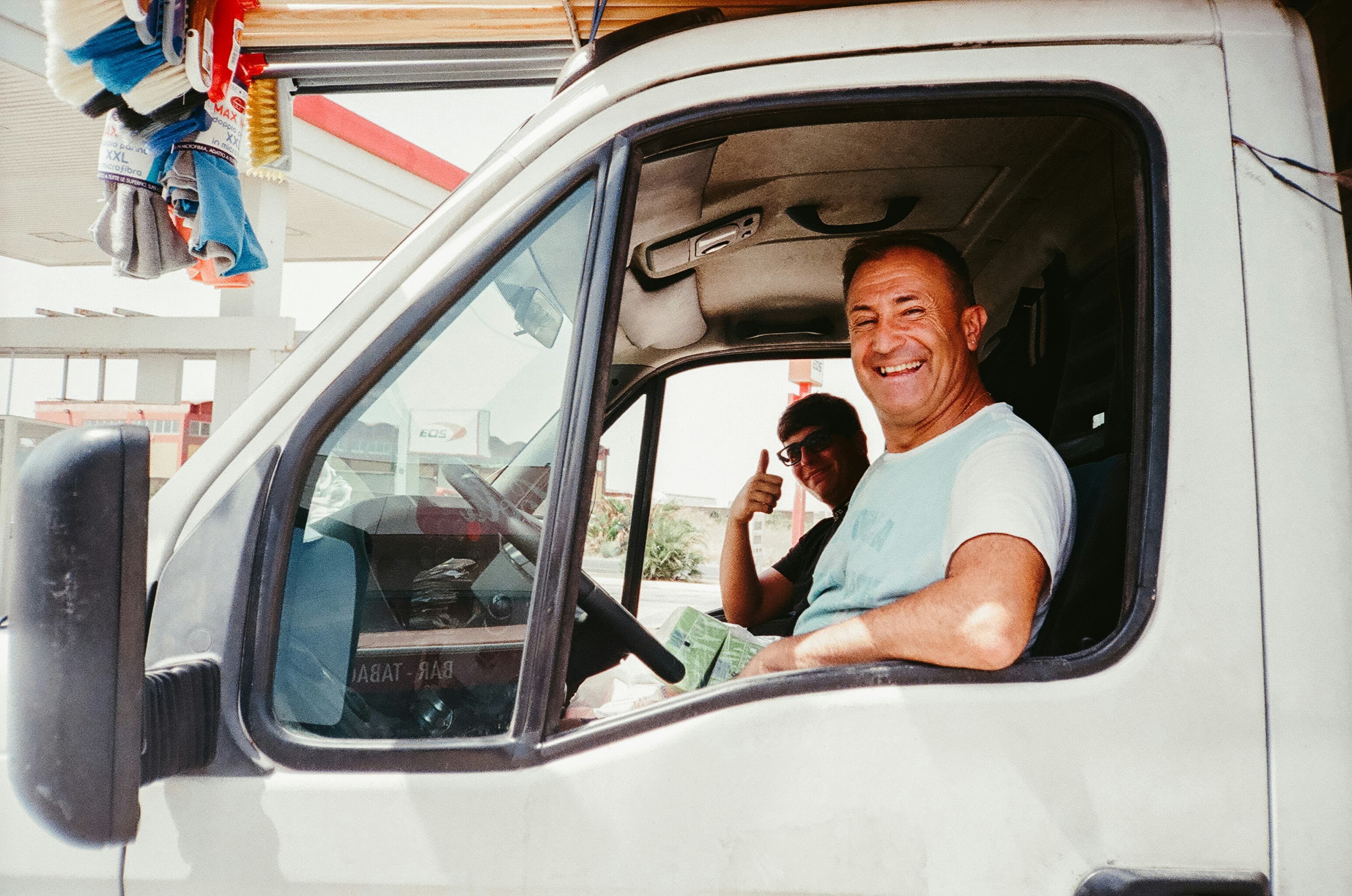 Two delivery drivers smiling from a van window