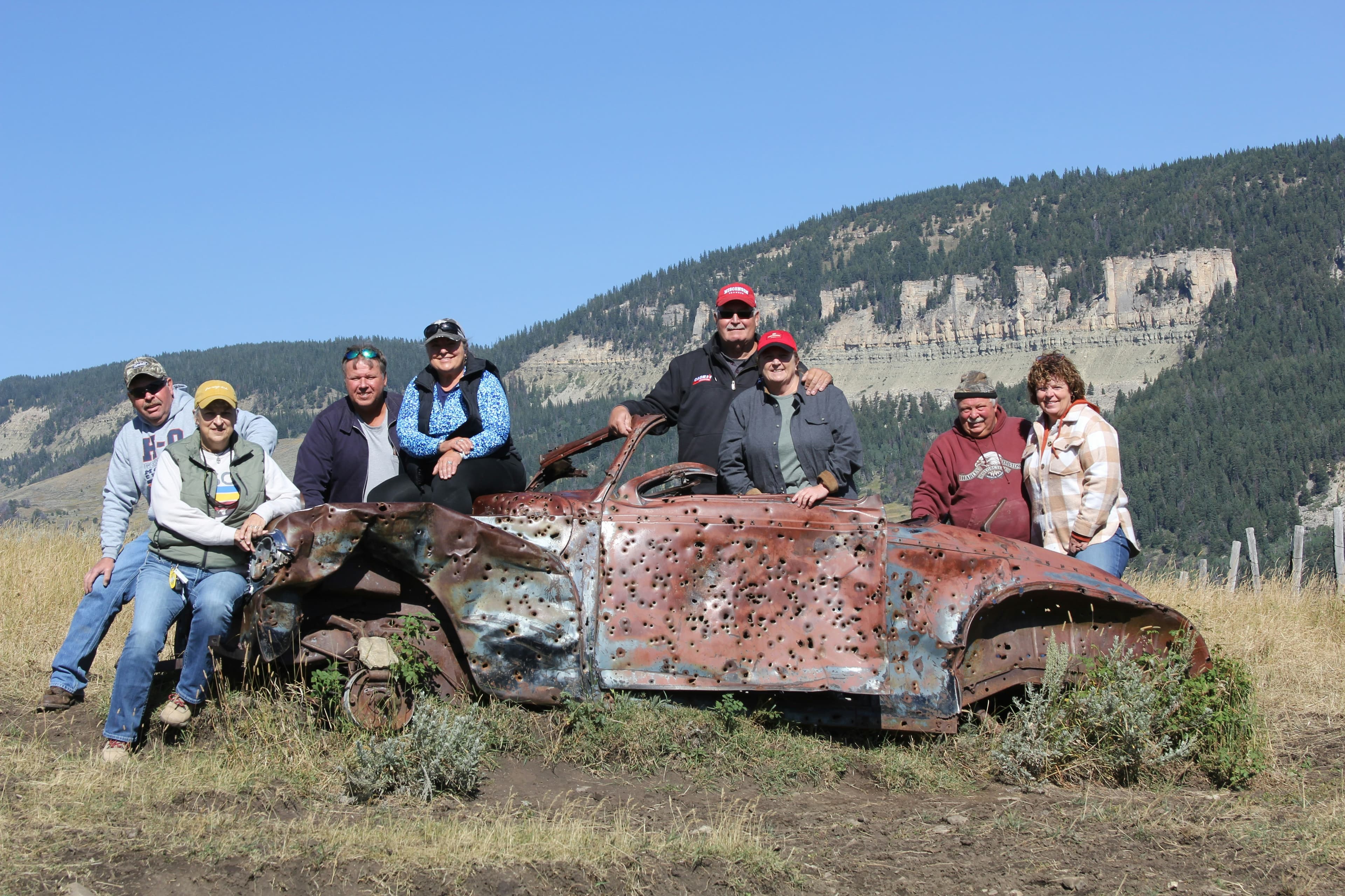 A group of people standing around an old car