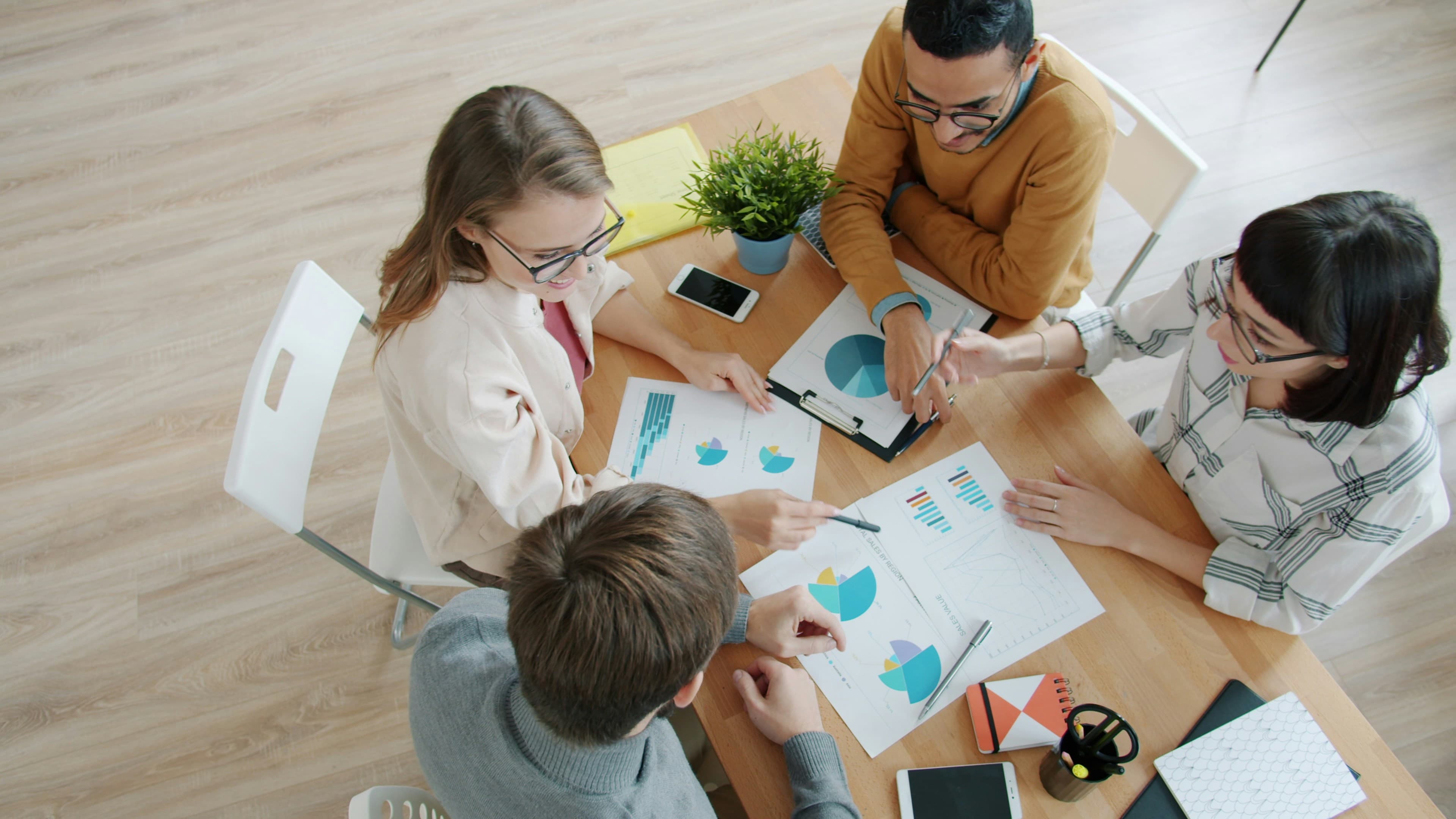 Four people collaborating around a table with charts